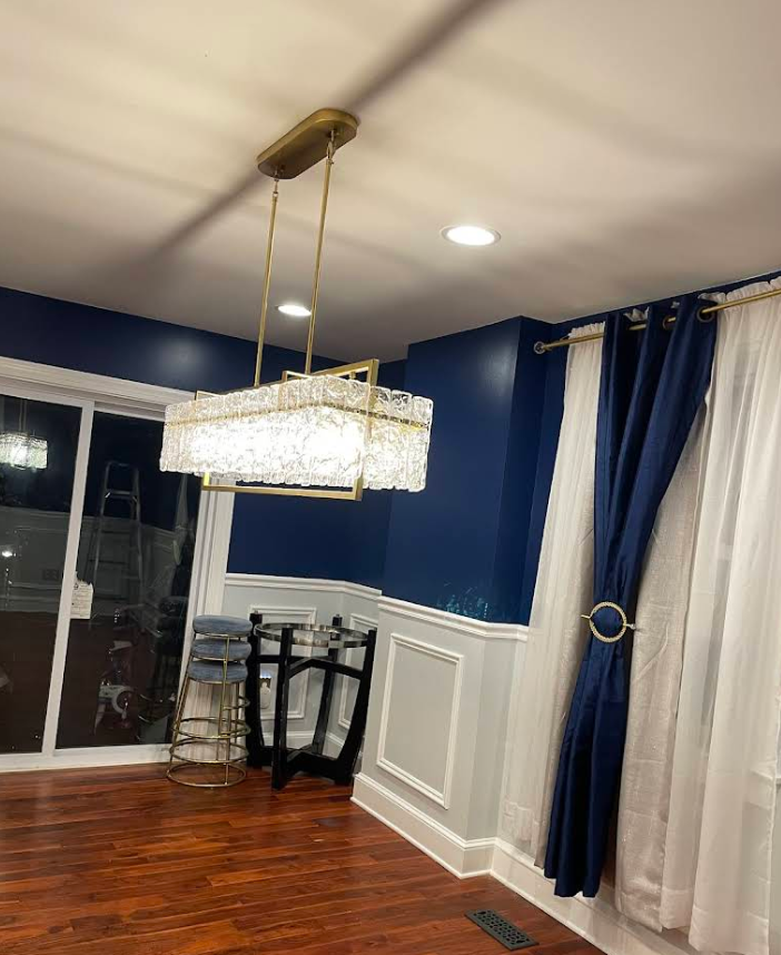 Crystal chandelier installed in dining room with blue walls and hardwood floors